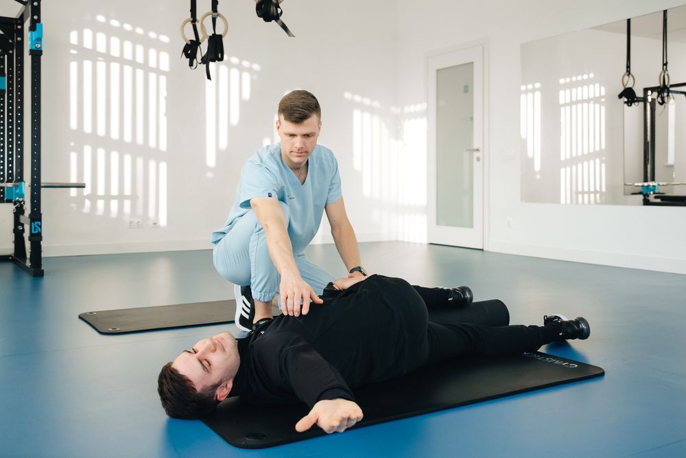 Physiotherapist helping a patient with a supported floor stretch