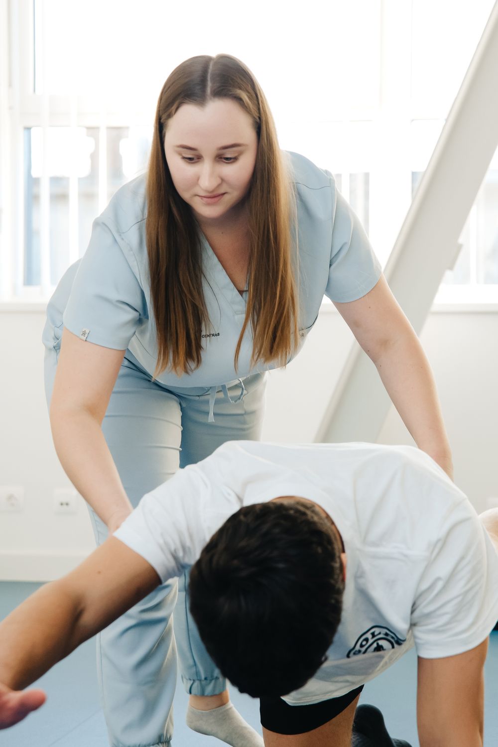 Physiotherapist supporting a patient during a floor exercise